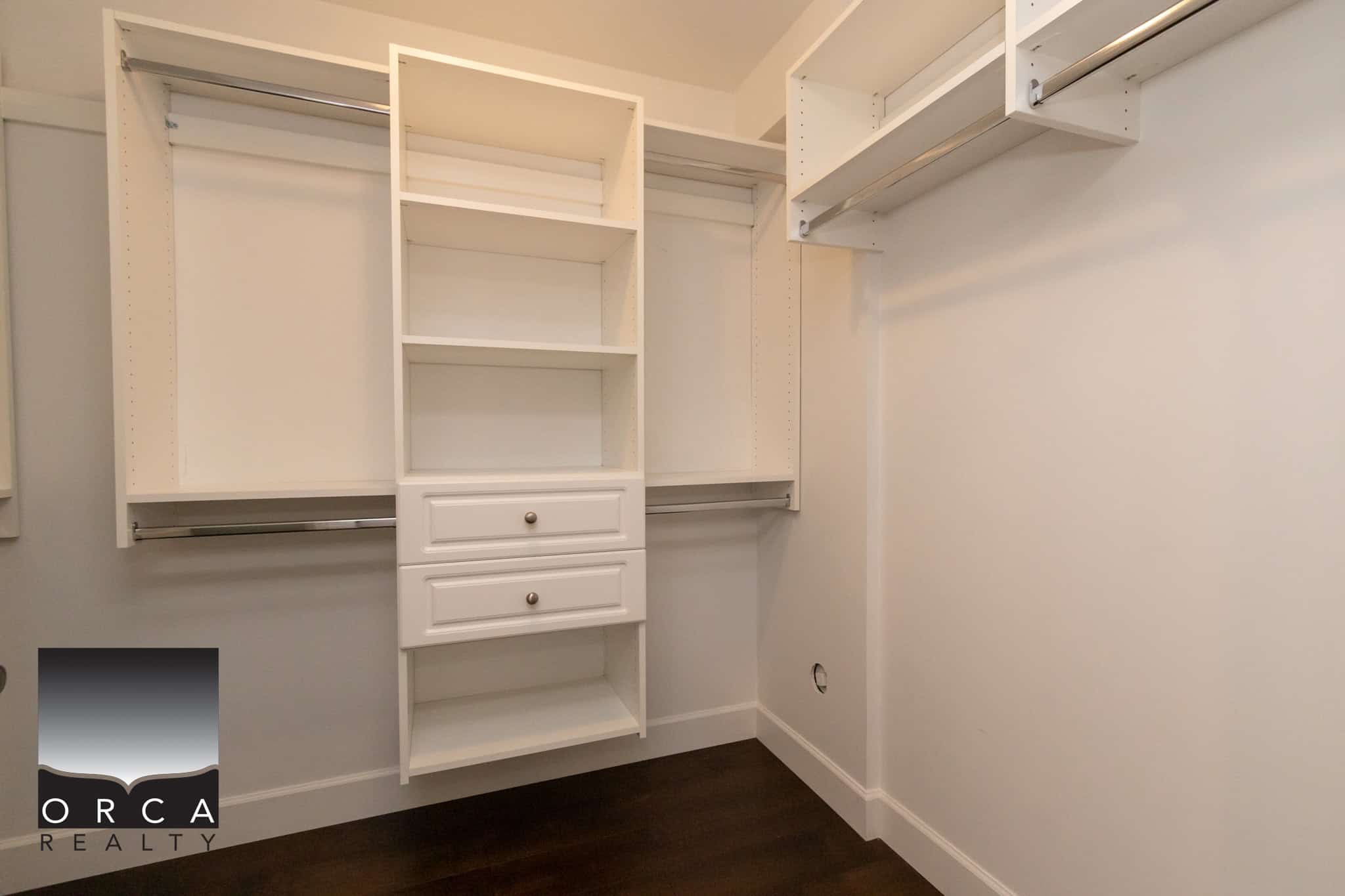 Spacious walk-in closet with custom white shelving and hanging rods for organized storage, ideal for modern home interiors and real estate listings in Vancouver.