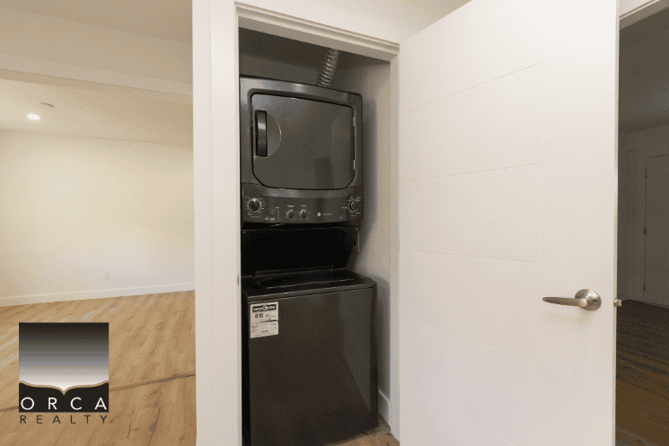 Stacked washer and dryer in a closet, modern laundry area, clean white walls, convenient home appliance setup, ideal for contemporary apartments or condos.