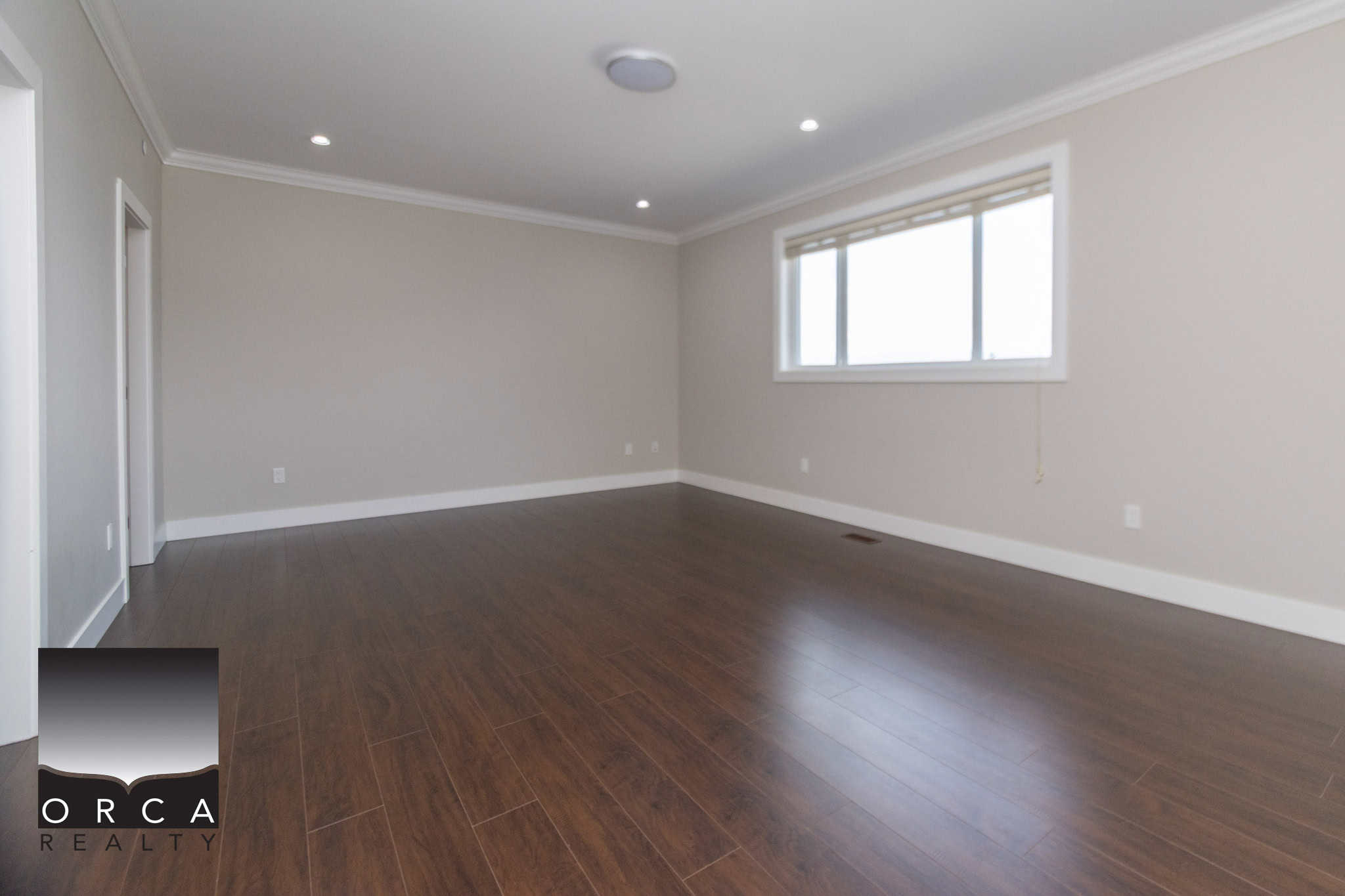 Bright empty living room with hardwood floors and large window, ideal for homebuyers seeking modern Vancouver area real estate.