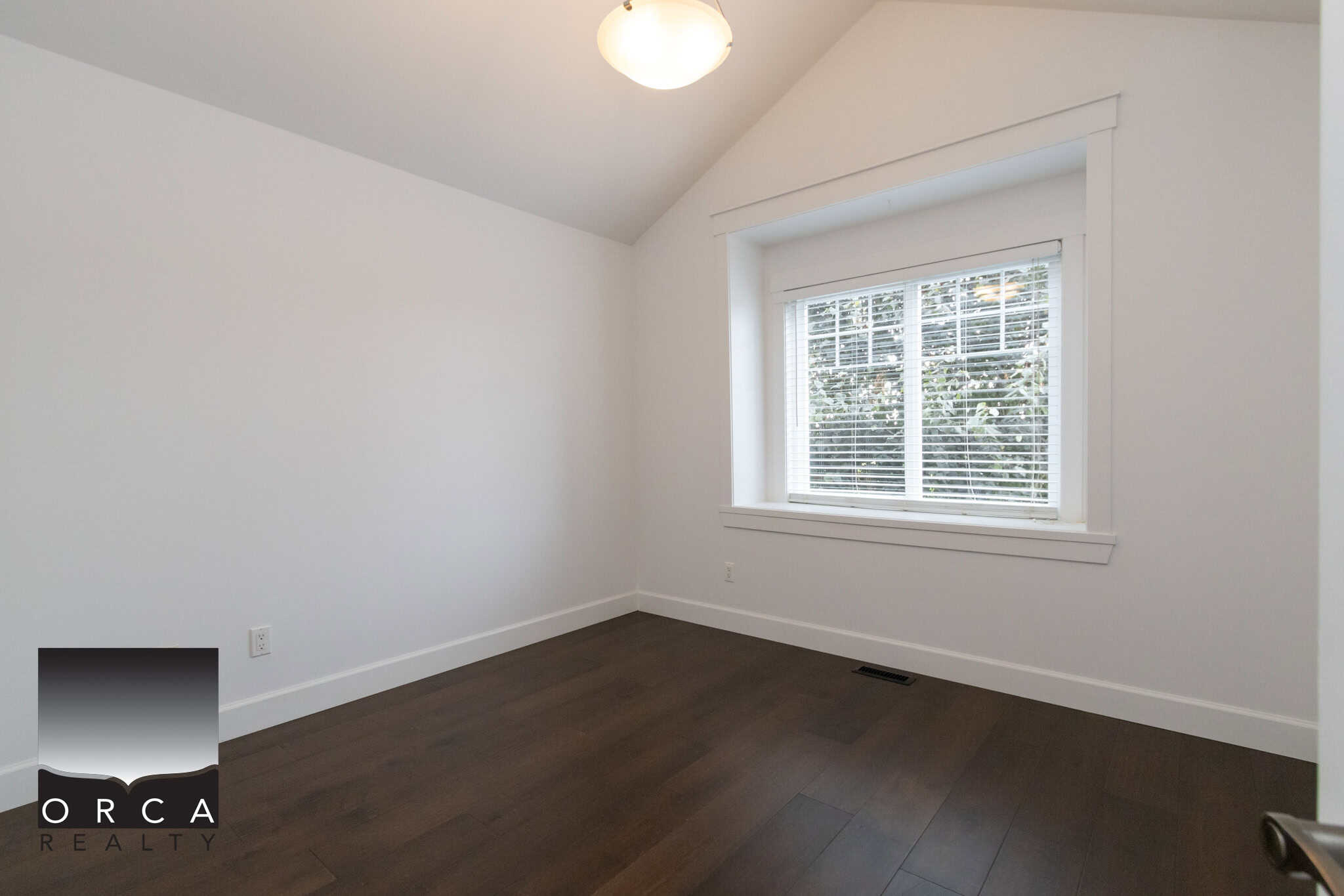 Bright, spacious bedroom with large window, white walls, hardwood flooring, and ample natural light, ideal for a cozy home setting in Victoria, BC.