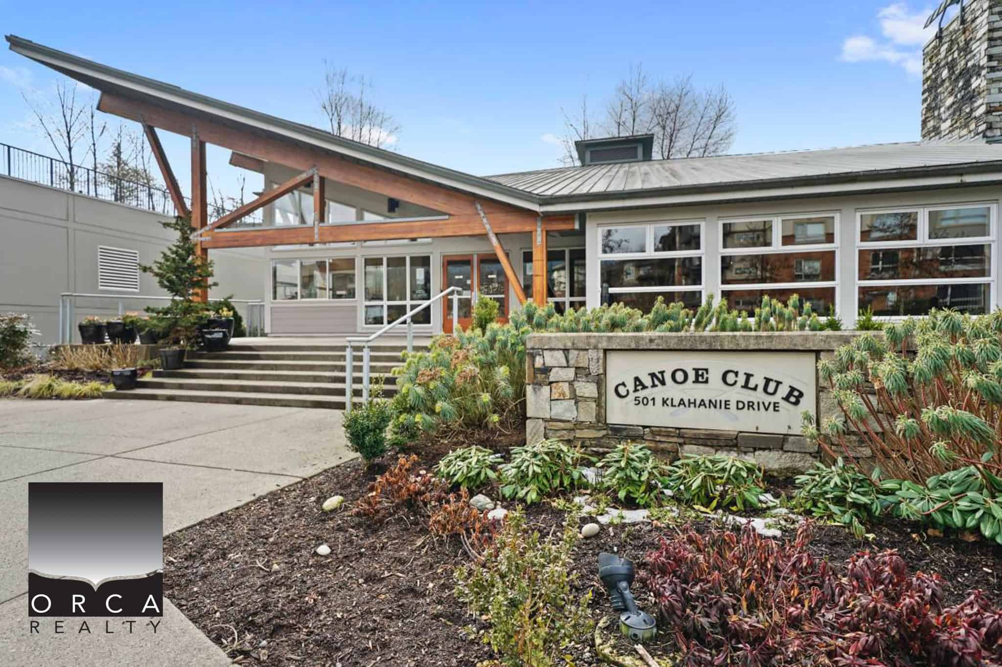 Modern condo building at Cane Club, 501 Klahanie Drive, featuring large windows, outdoor landscaping, and community charm in a prime location.