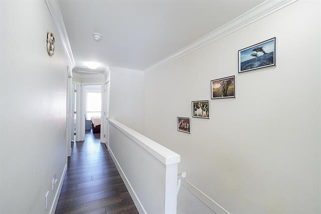 Modern hallway with white walls and dark wood flooring, featuring framed ocean and nature artwork, leading to a bright bedroom in a contemporary home.