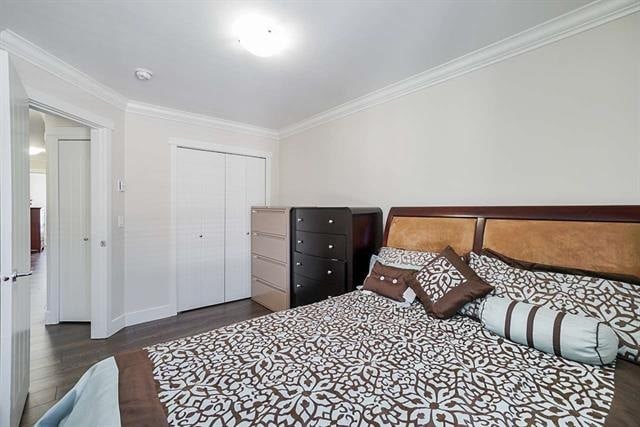 Bright spacious bedroom with modern furniture, including a large bed with patterned bedding and a mix of dressers, in a well-lit, clean interior space.