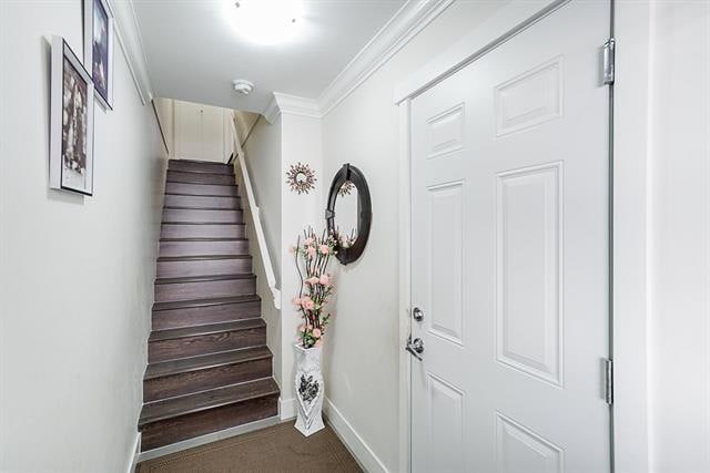 Wooden staircase in modern home interior with decorative mirror and floral arrangement, showcasing stylish entryway design by Orca Realty Inc.