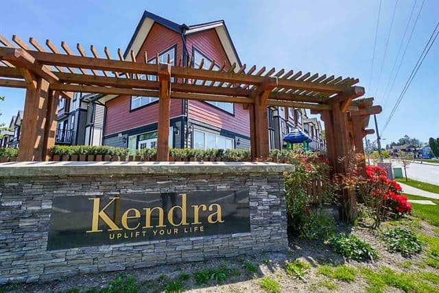Contemporary multi-family residential building with landscaped garden and Kendra sign, in a vibrant Vancouver neighbourhood.