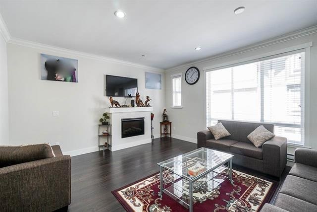 Modern living room with large windows, cozy sofas, and a sleek fireplace, perfect for Vancouver real estate buyers. Well-lit interior with contemporary decor and hardwood flooring.