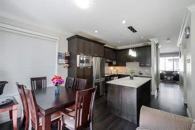 Modern kitchen and dining area with dark wood cabinets and stainless steel appliances at Orca Realty Inc. in en_CA.