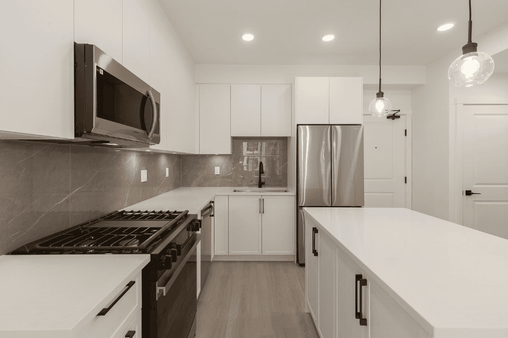 Modern kitchen with white cabinetry, stainless steel appliances, and a sleek island, ideal for your Vancouver Island home or investment property. Fully equipped for comfortable living and entertaining.