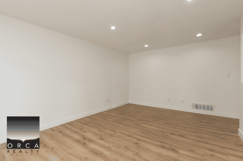 Spacious modern empty living room with hardwood floors and neutral white walls, perfect for showcasing Vancouver Island real estate opportunities.