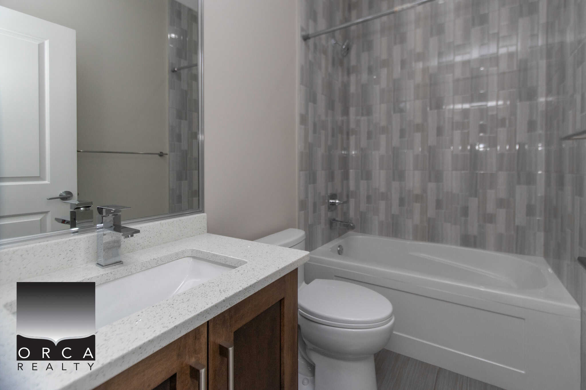 Modern bathroom with stylish grey tile accents, white bathtub, and contemporary fixtures, showcasing quality interior design for Vancouver real estate listings.