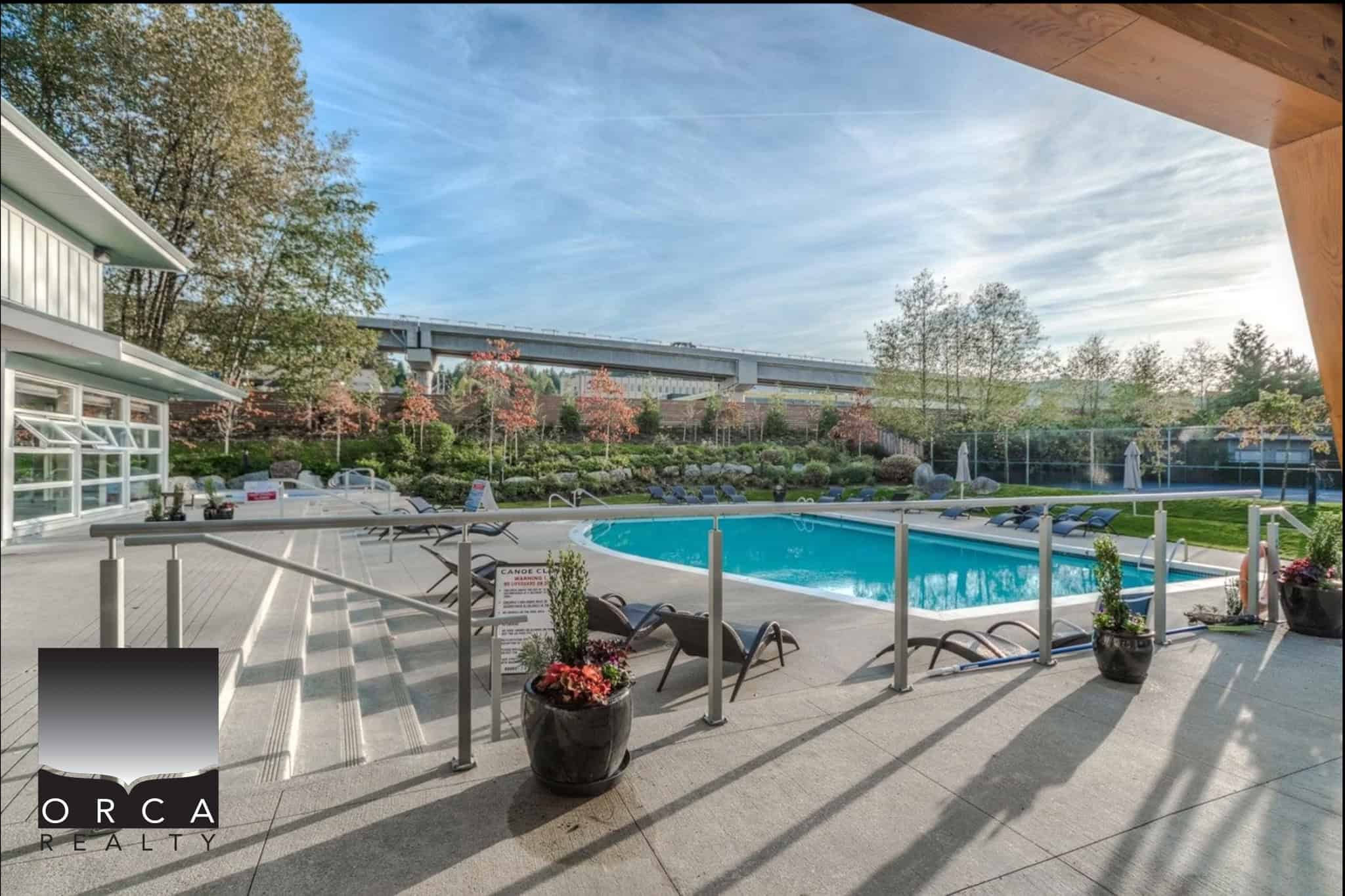 Relaxing outdoor swimming pool area at Orca Realty Inc. featuring lounge chairs, landscaped gardens, and scenic views, perfect for residents and visitors to enjoy Vancouver’s outdoor lifestyle.