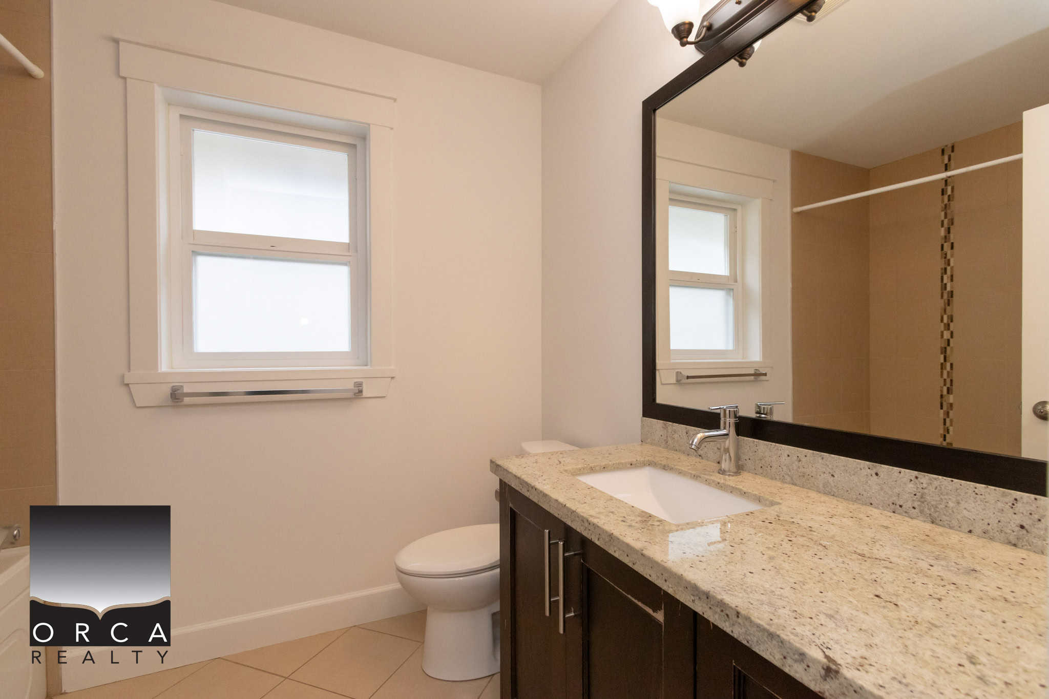 Modern bathroom with white walls, frosted double windows, beige tiled floors, and a granite countertop vanity featuring a large mirror, chrome fixtures, and a cozy walk-in shower, ideal for Vancouver Island living.