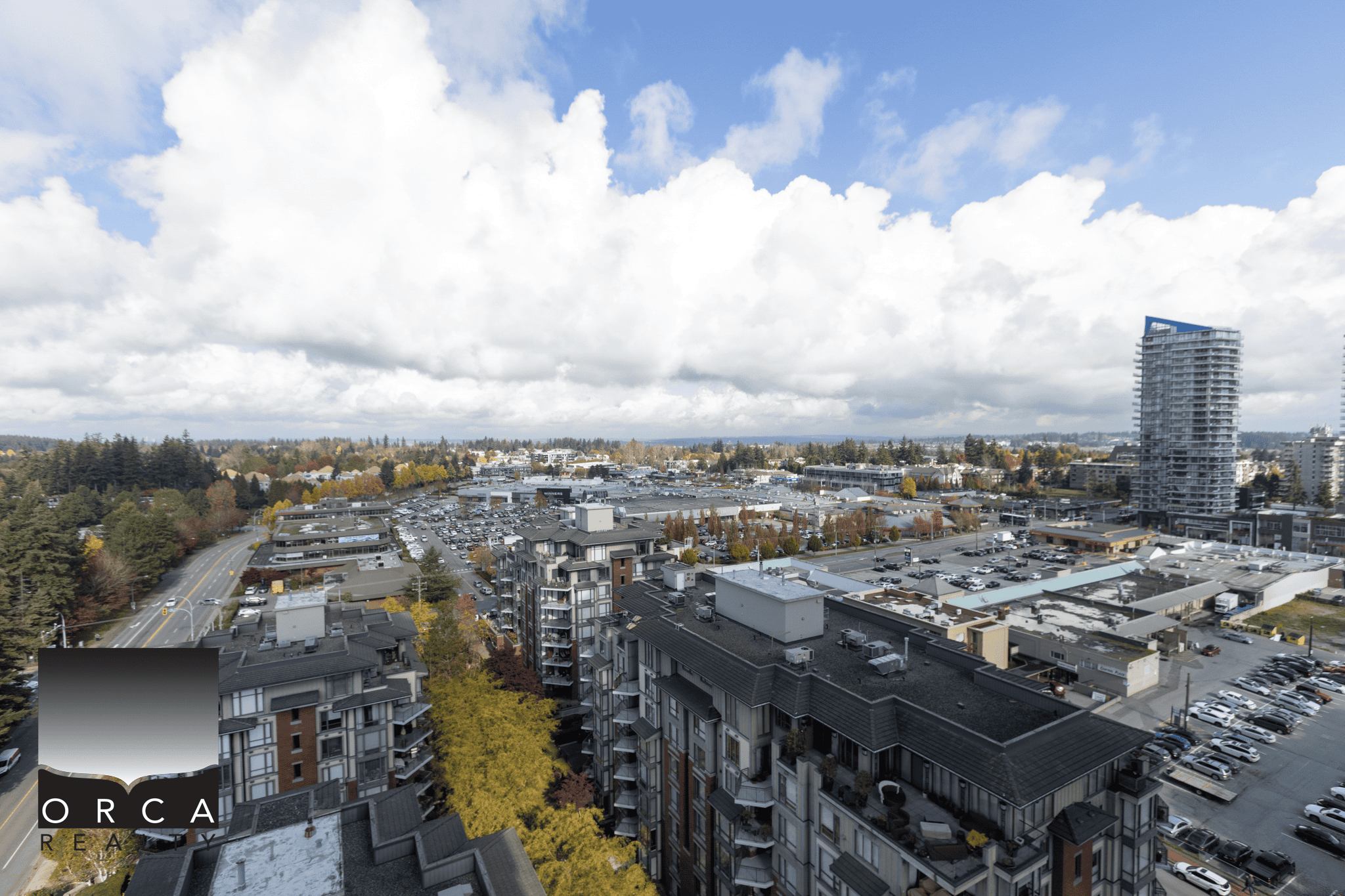 Vibrant urban cityscape showcasing commercial and residential buildings, parking areas, and lush surroundings, emphasizing Orca Realty Inc.'s expertise in Vancouver real estate and property management.