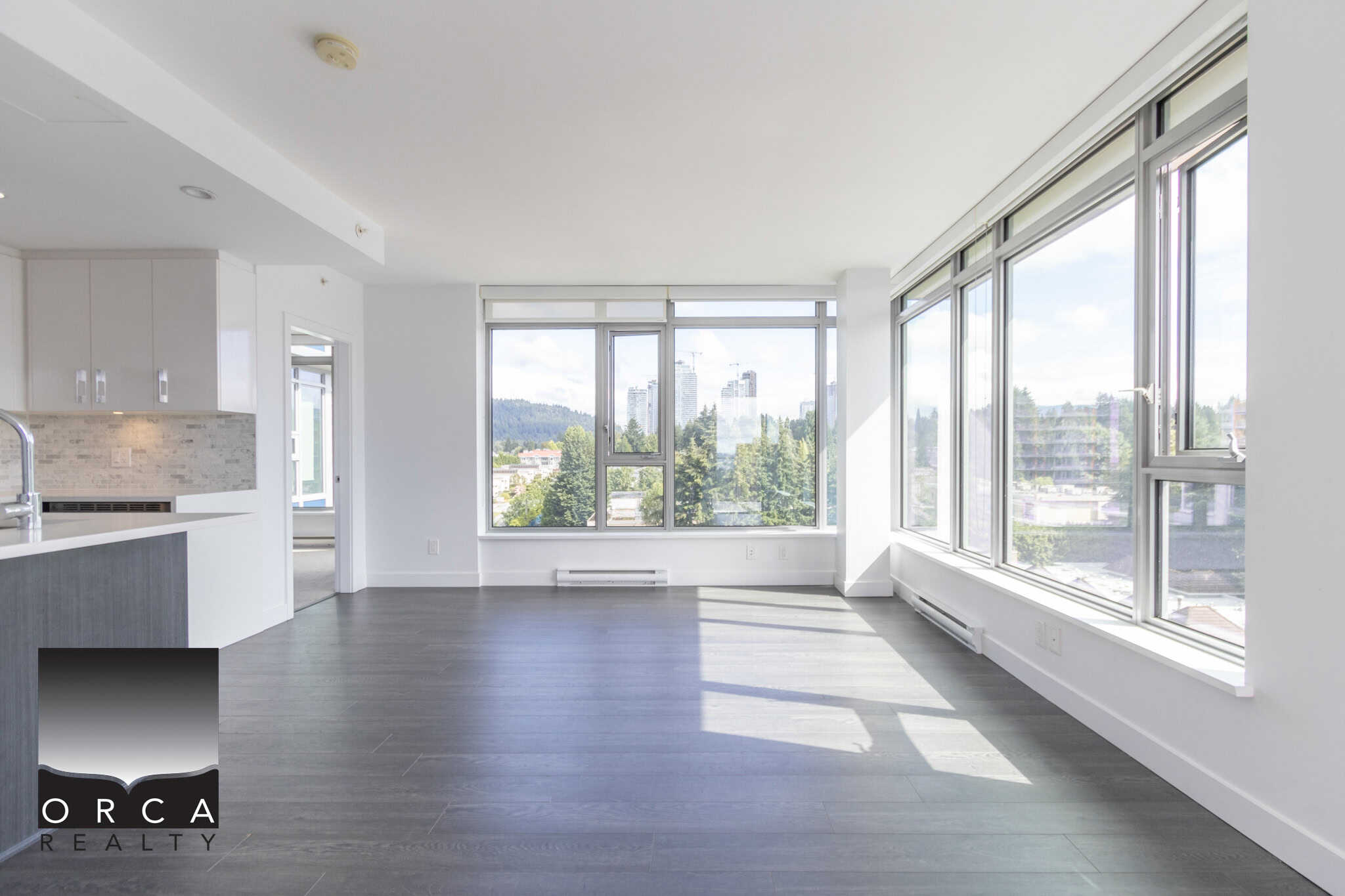 Bright modern living room with large windows offering stunning city views and natural light in a downtown Vancouver condo, featuring sleek flooring and open concept design.