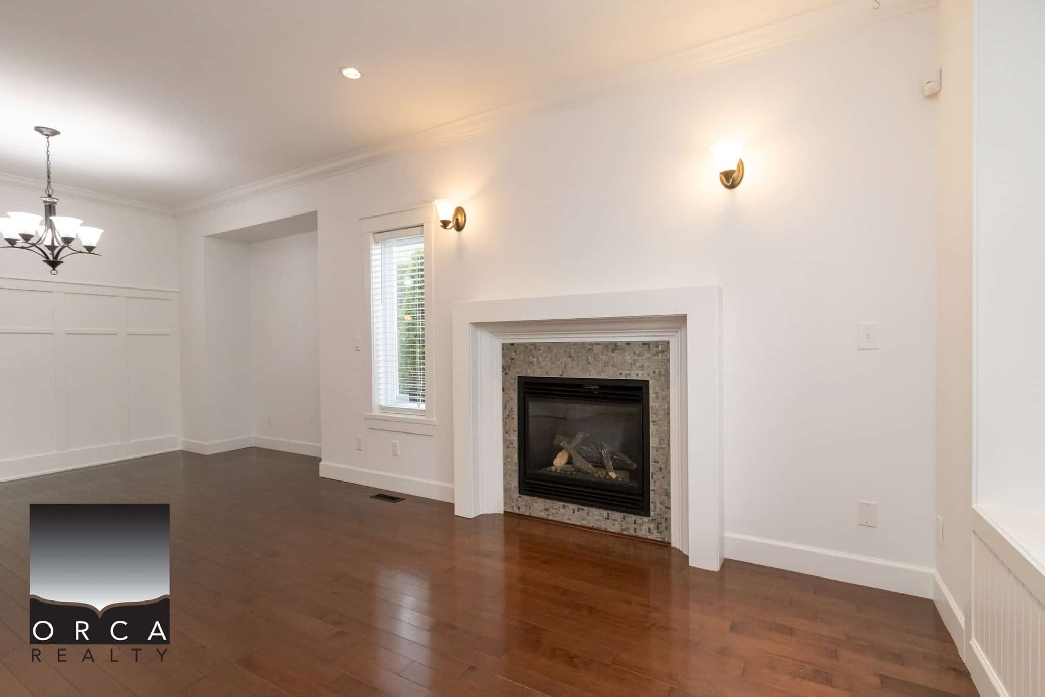 Spacious living room with a cozy fireplace, hardwood flooring, and modern lighting fixtures, ideal for family gatherings and entertaining guests in a Vancouver area home.