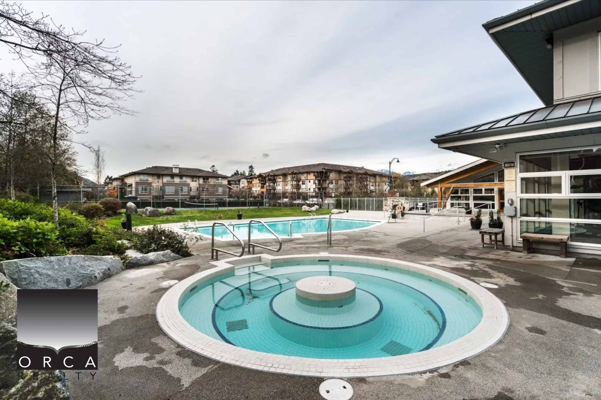 Relaxing outdoor swimming pool and hot tub at Orca Realty Inc. property in British Columbia, featuring landscaped surroundings and modern amenities, ideal for residents and visitors.