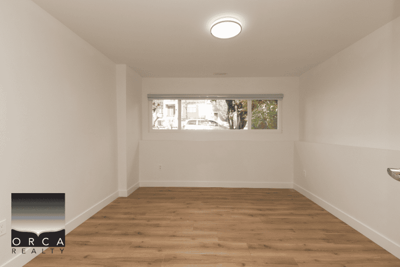 Bright empty living room with large window, white walls, and laminate flooring, ideal for real estate listings and home staging in Vancouver, B.C.