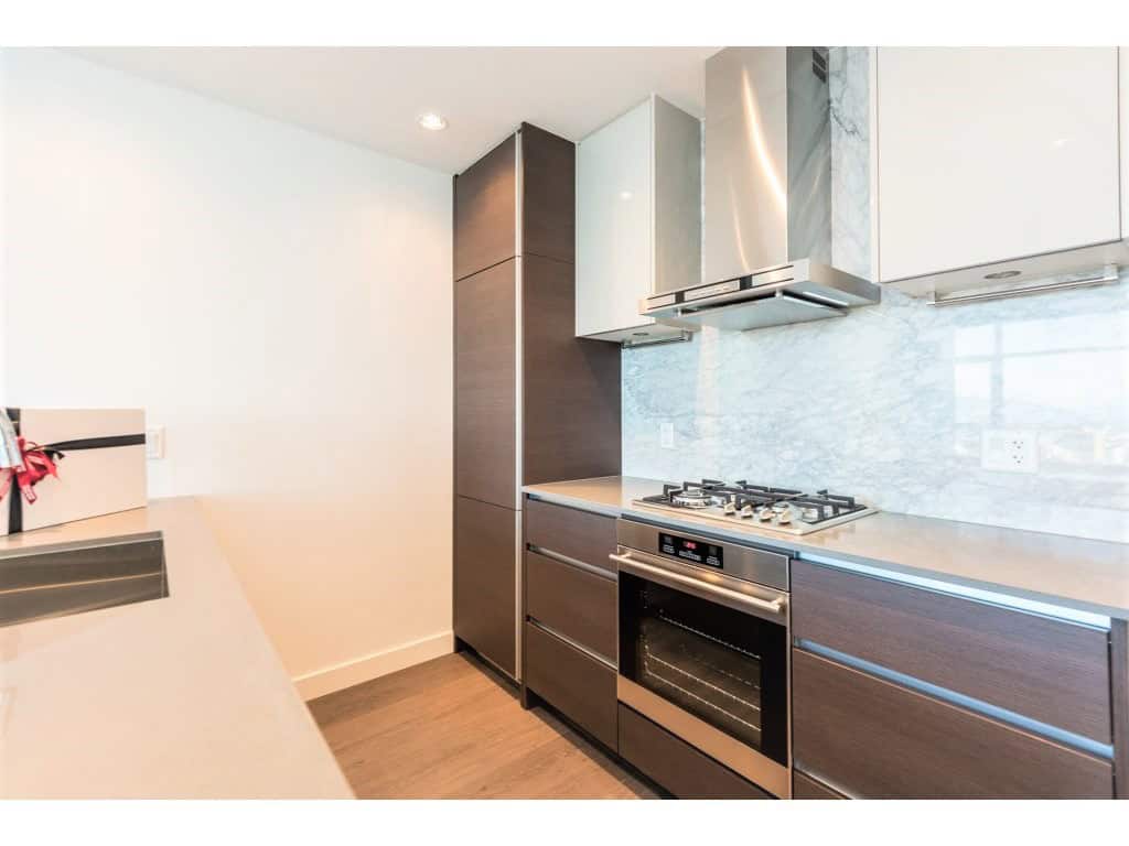 Modern kitchen with stainless steel appliances, dark wood cabinetry, and marble backsplash for contemporary Vancouver home living.