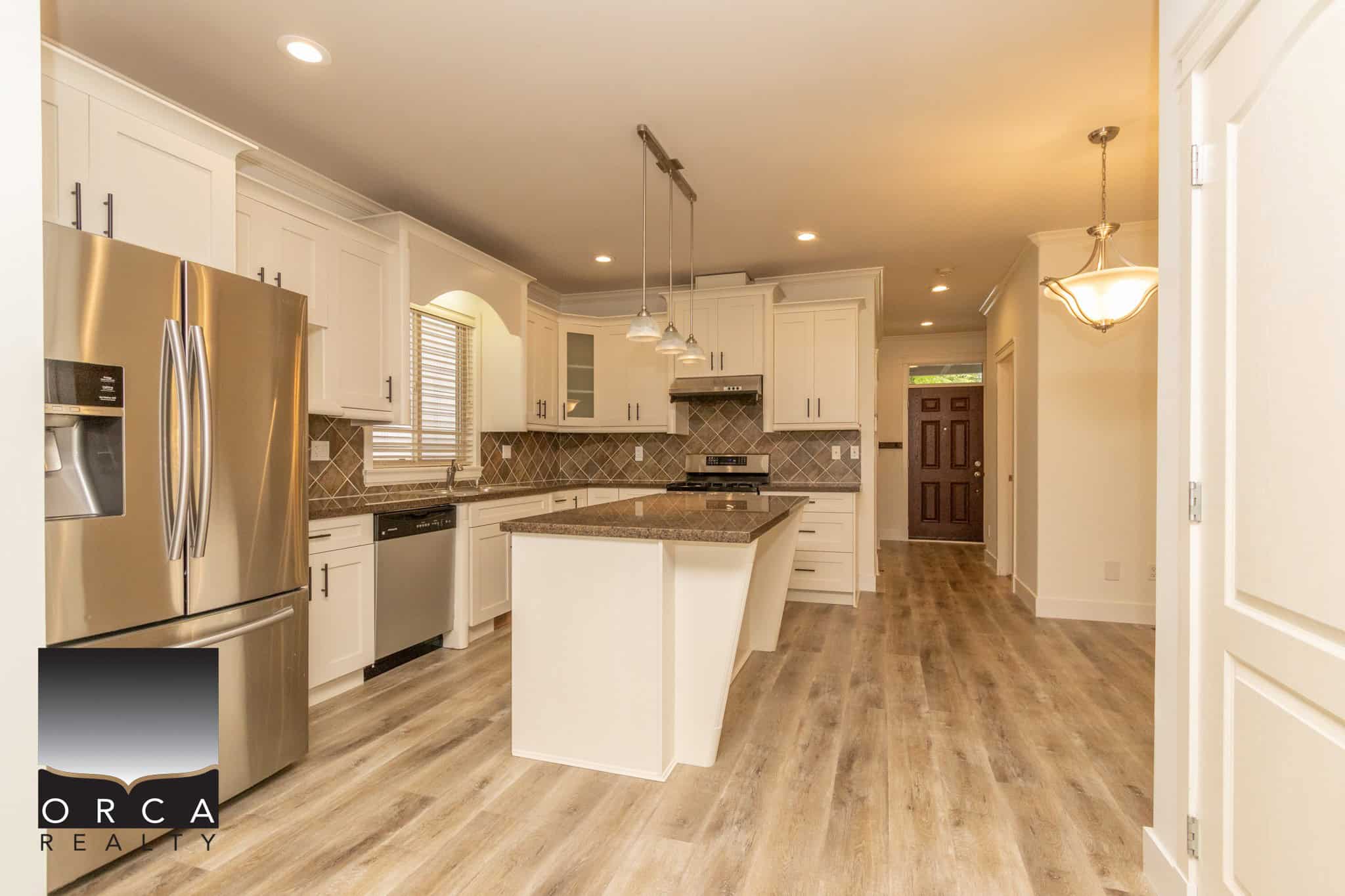 Stunning modern kitchen with stainless steel appliances, white cabinetry, granite countertops, and under cabinet lighting in a contemporary home.
