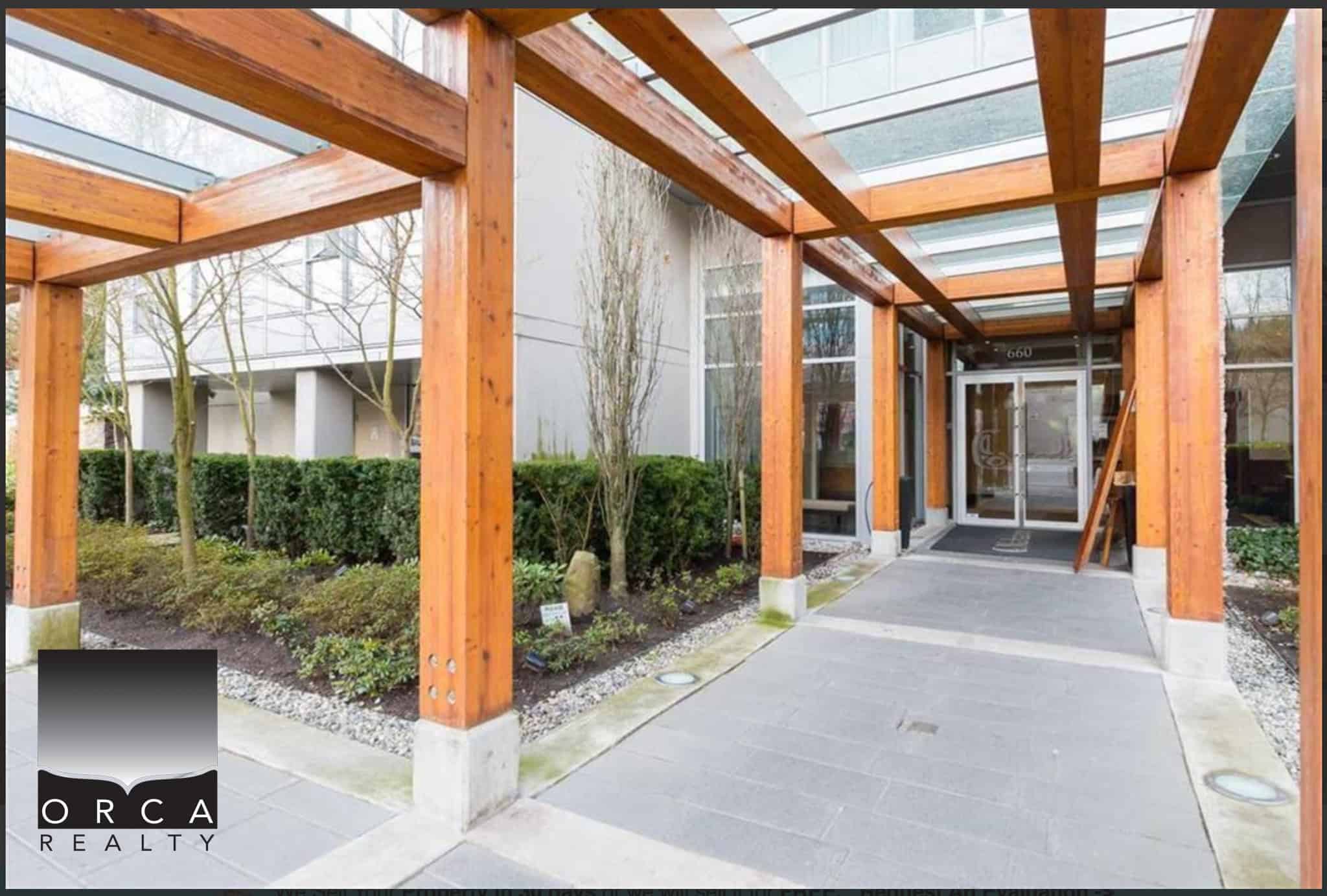 Modern commercial building entrance with wooden pergola and landscaped greenery, showcasing professional office exterior in Vancouver, British Columbia.