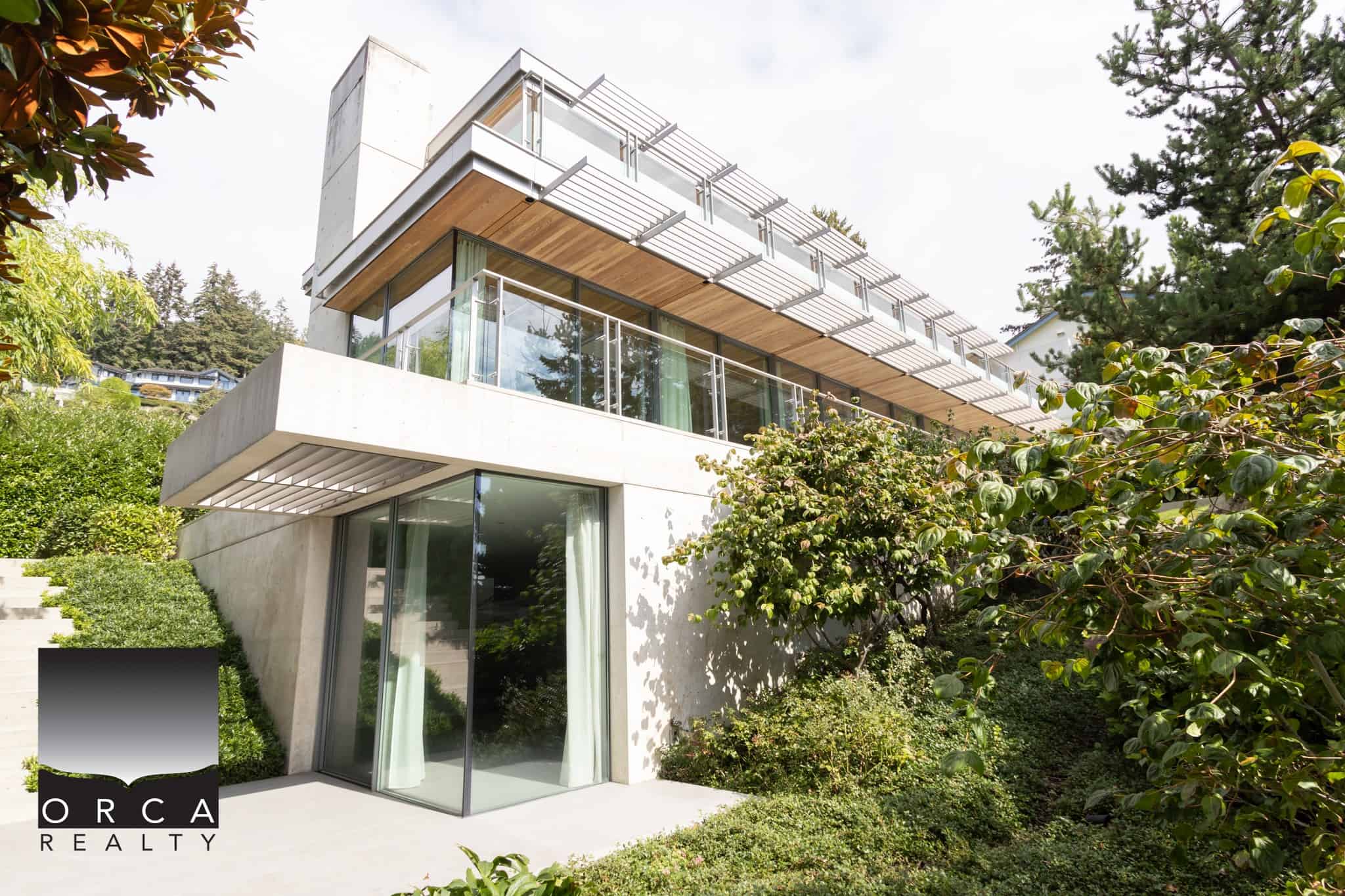 Contemporary modern house with large glass windows and lush greenery, showcasing upscale architectural design, perfect for luxury real estate in Vancouver, BC.