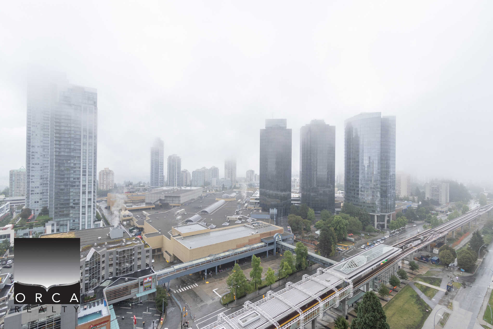 Modern Vancouver city skyline with high-rise glass buildings and foggy weather, showcasing downtown commercial real estate and urban lifestyle in British Columbia.