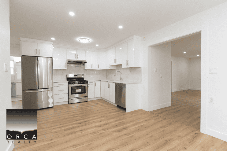 Modern kitchen with stainless steel appliances and white cabinetry in a new residential home - Orca Realty Inc.