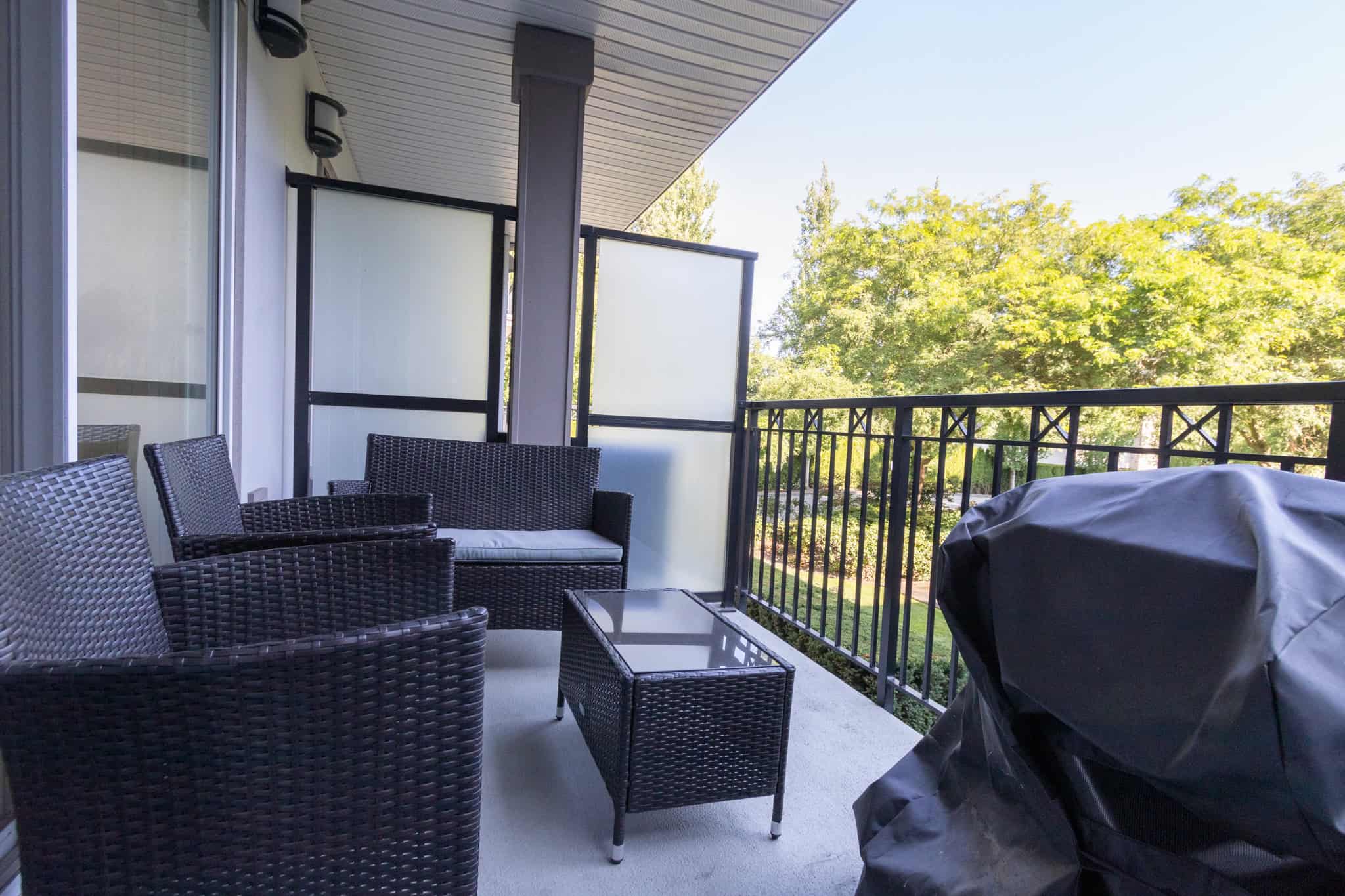 6 Spacious balcony with outdoor wicker furniture and a barbecue grill, offering a relaxing space to enjoy nature and fresh air in a desirable urban neighborhood.