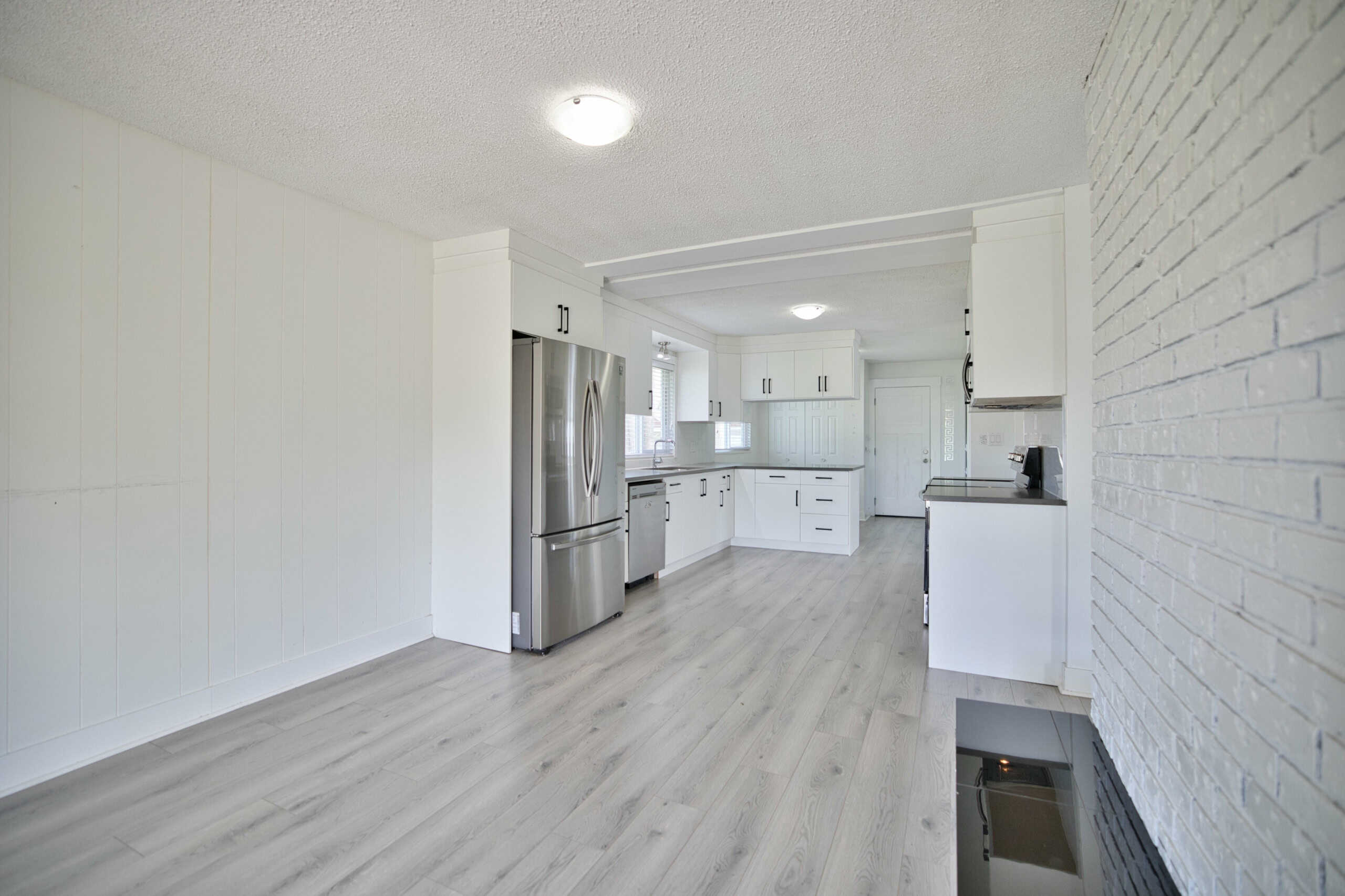 Bright modern kitchen with white cabinets, stainless steel appliances, and light wood flooring, ideal for Vancouver Island real estate photos for Orca Realty Inc.