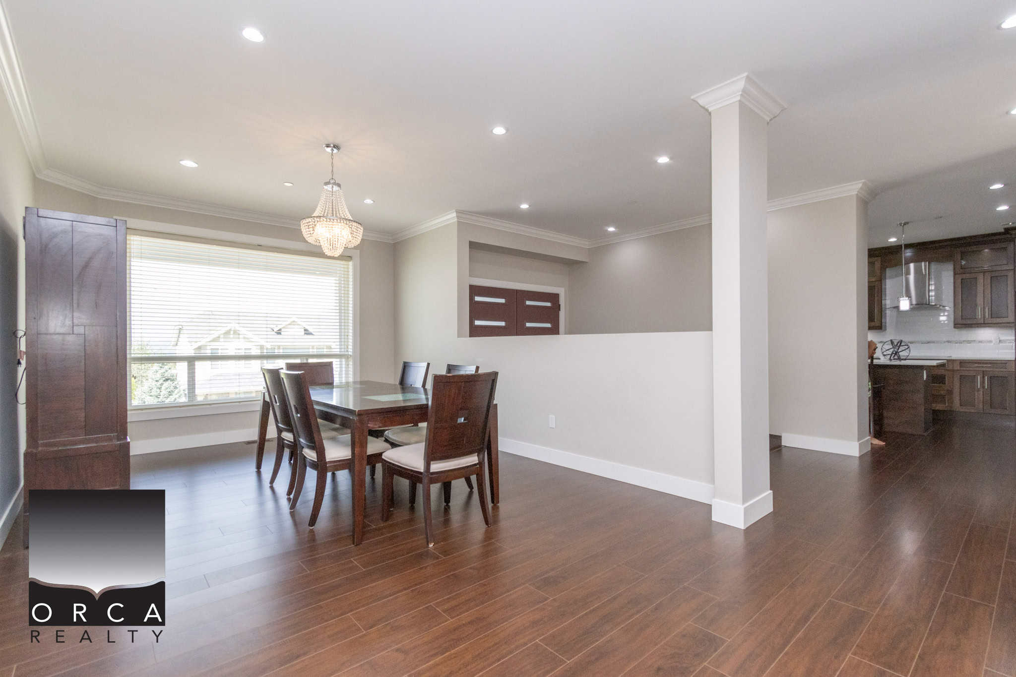 Spacious dining area with large window, modern kitchen, hardwood floors, and elegant lighting, perfect for family meals and entertaining in a well-maintained home.