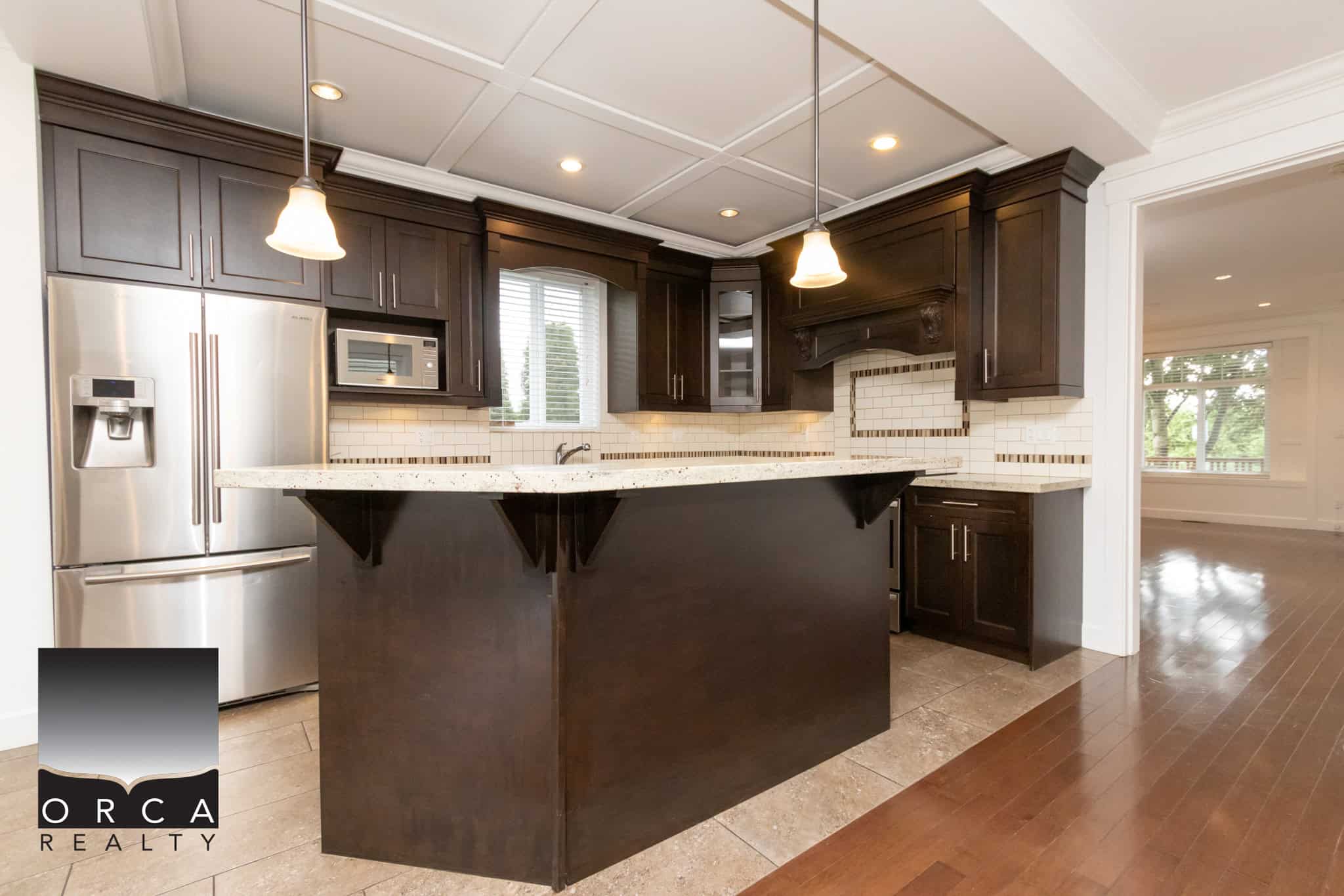 Stunning modern kitchen with dark wood cabinetry, stainless steel appliances, and a granite countertop island, perfect for Calgary real estate buyers seeking elegant home features.