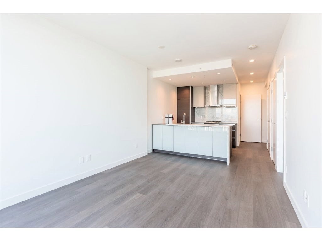 Contemporary kitchen and open living space in a modern Vancouver condo, featuring sleek cabinetry, stainless steel appliances, and hardwood flooring, ideal for Vancouver real estate buyers.