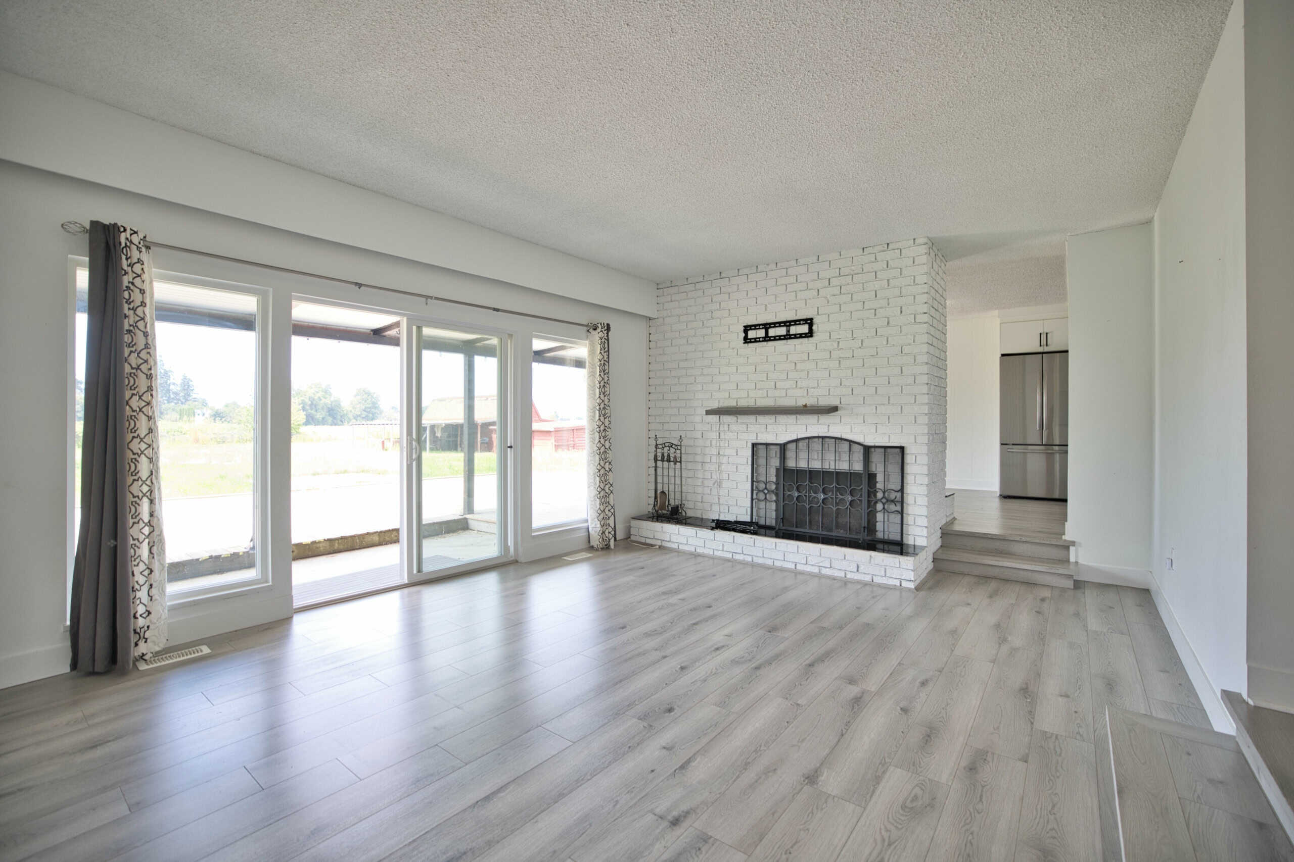 Bright living room with white brick fireplace, large sliding glass doors for natural light, modern open-concept design, ideal for Ottawa real estate listings.
