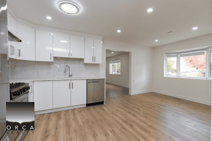 Bright, modern kitchen with white cabinetry and stainless steel appliances in a spacious, open-concept living area. Perfect for family living and entertaining in Vancouver houses.