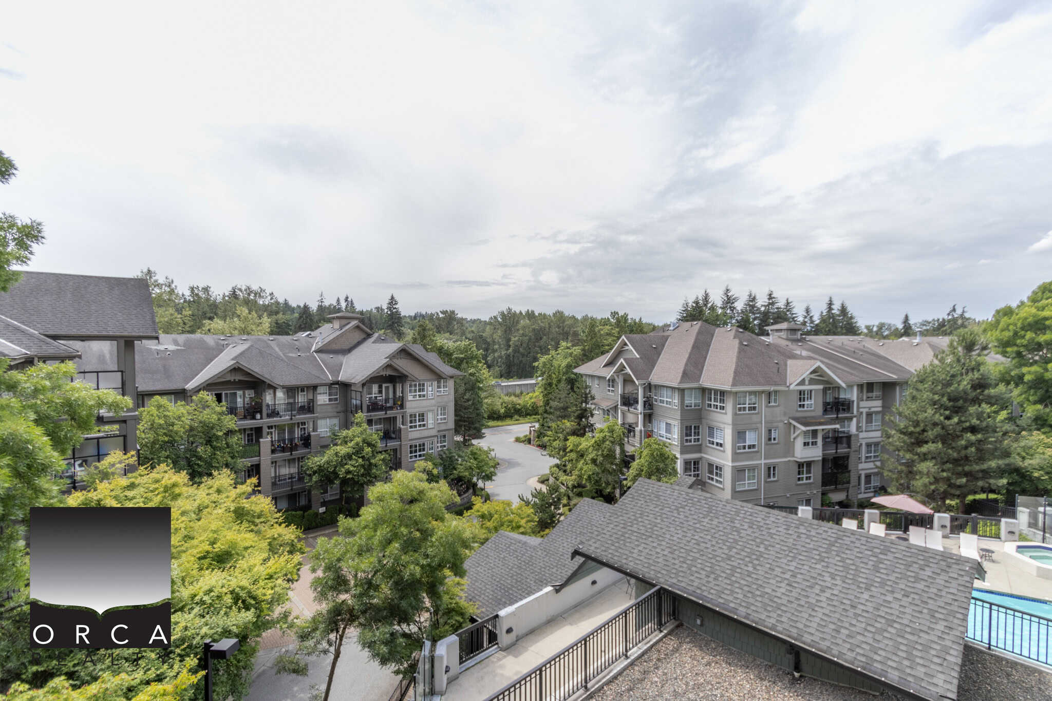 Modern apartment complex in a serene residential community surrounded by lush greenery and mature trees, showcasing well-maintained buildings and amenities like a swimming pool.
