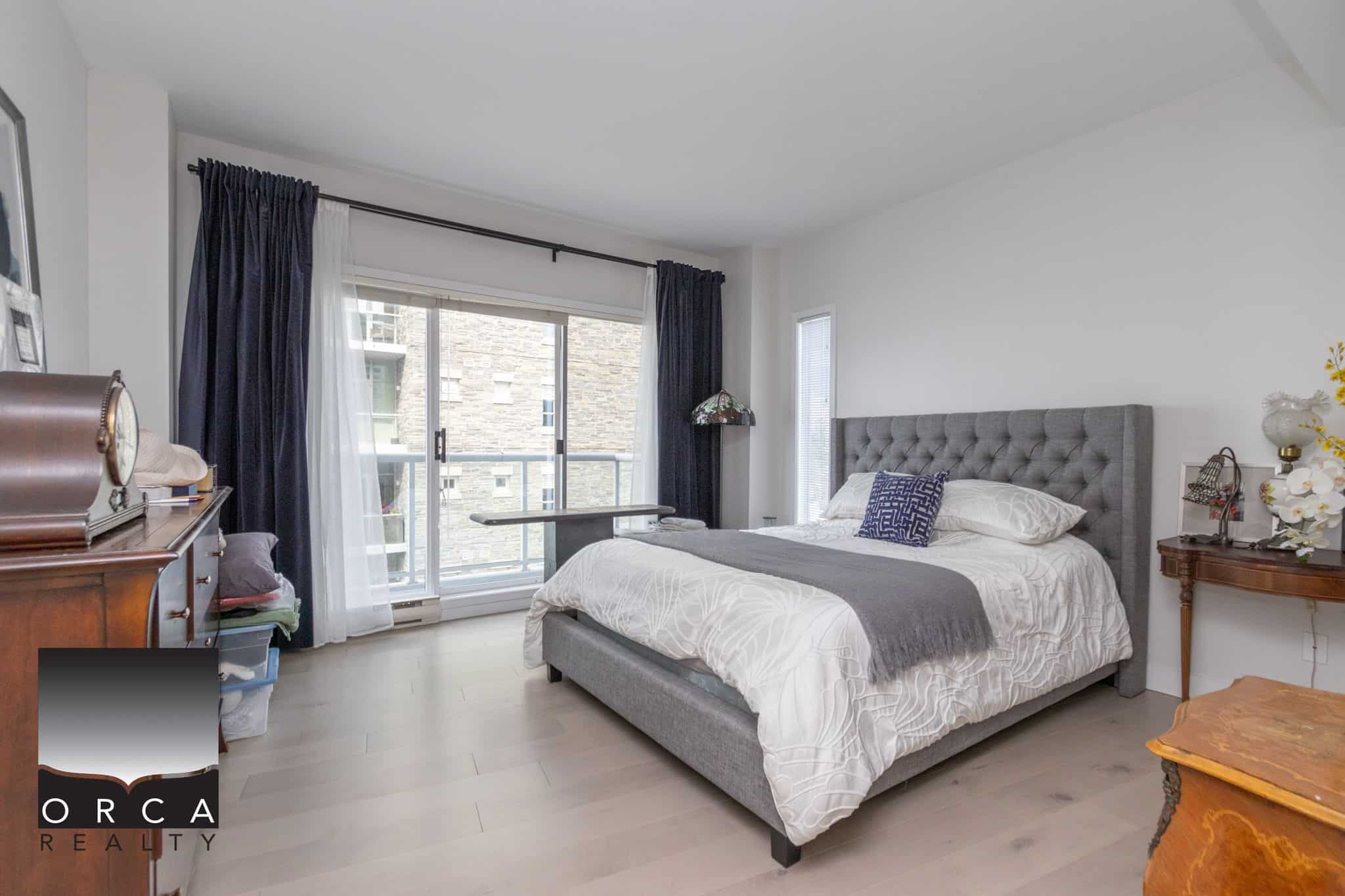 Bright modern bedroom with balcony access and natural light, featuring stylish decor and hardwood flooring, perfect for Vancouver real estate buyers seeking contemporary housing.