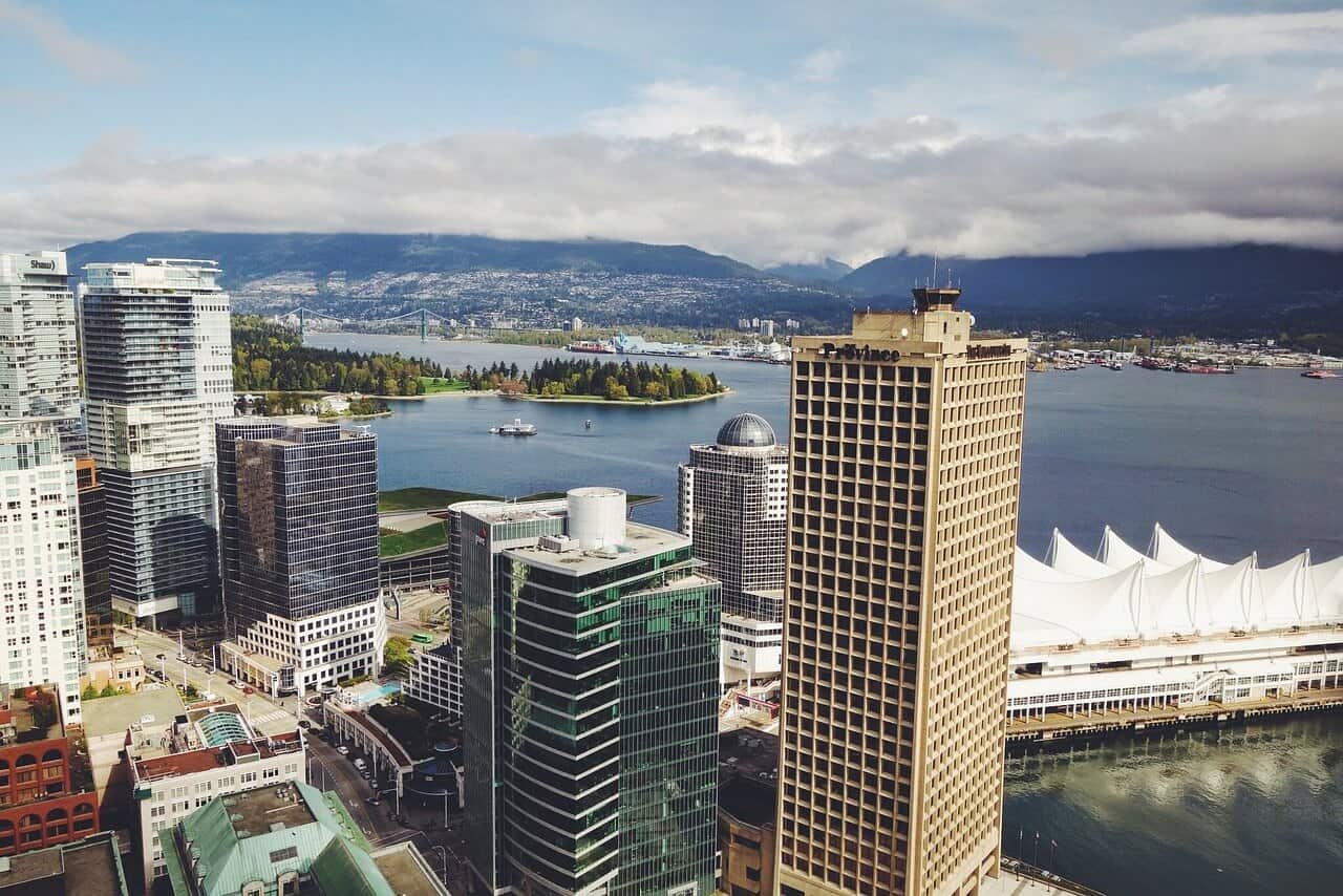 Breathtaking aerial view of Vancouver's downtown skyline with city skyscrapers, waterfront, and surrounding mountains, showcasing prime real estate opportunities with Orca Realty Inc.