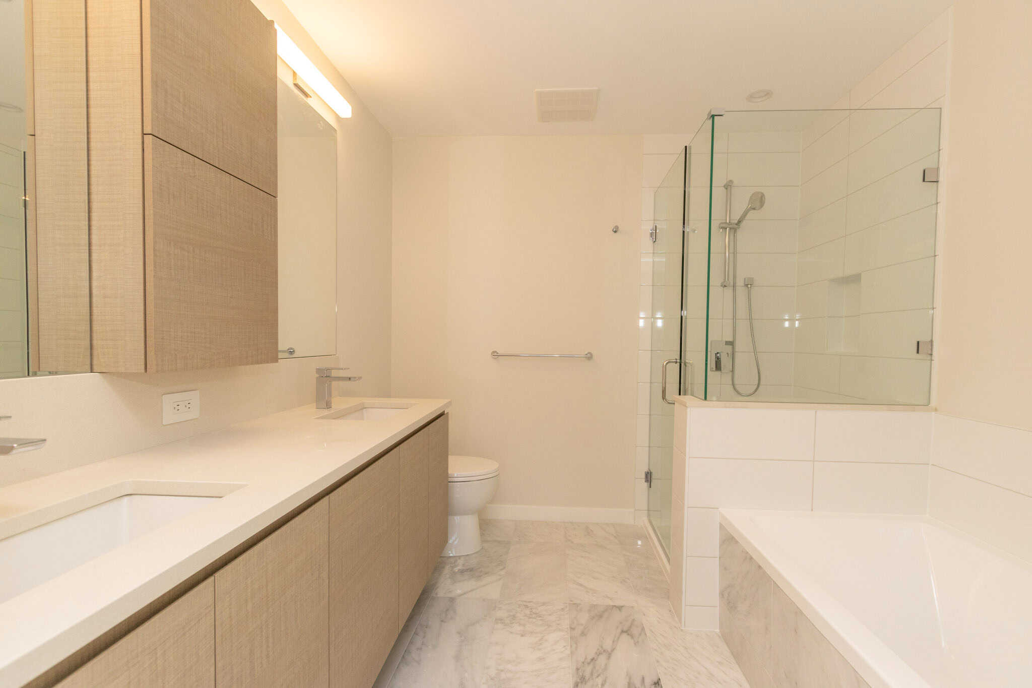 IMG_1600 Modern bathroom with double vanity, glass-enclosed shower, and bathtub, featuring neutral tones, marble flooring, and contemporary fixtures, ideal for luxury home living in BC.