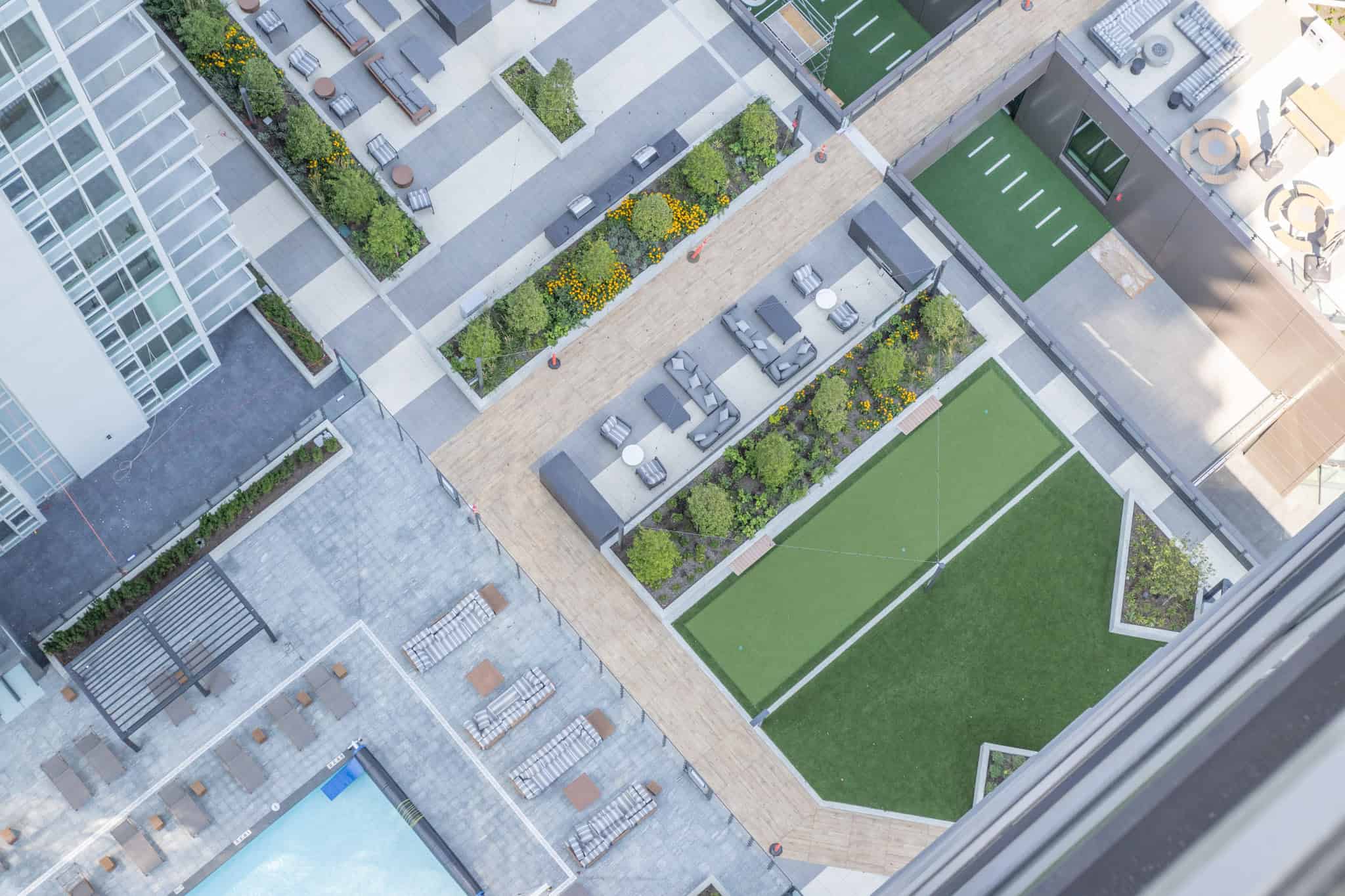 IMG_1690 Modern urban rooftop garden with seating areas, green lawns, and landscaped planters, ideal for condo living and community relaxation.