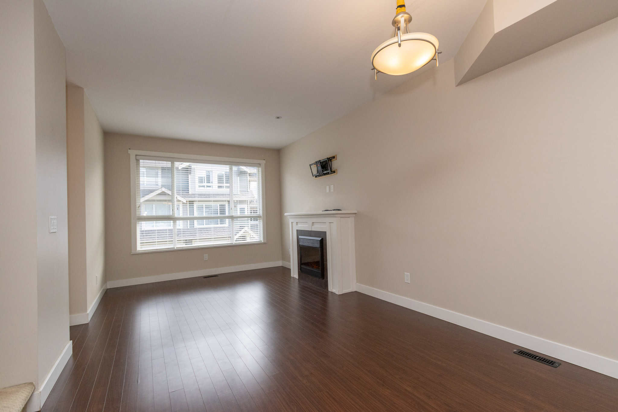 IMG_1769 Spacious living room with hardwood flooring and large window in a modern Vancouver home, featuring a cozy fireplace and neutral tones, ideal for comfortable family living.