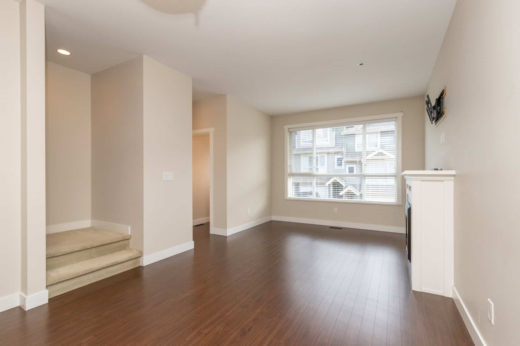 IMG_1773 Spacious living room with large windows and hardwood floors, showcasing modern interior design in a residential property listed by Orca Realty Inc.