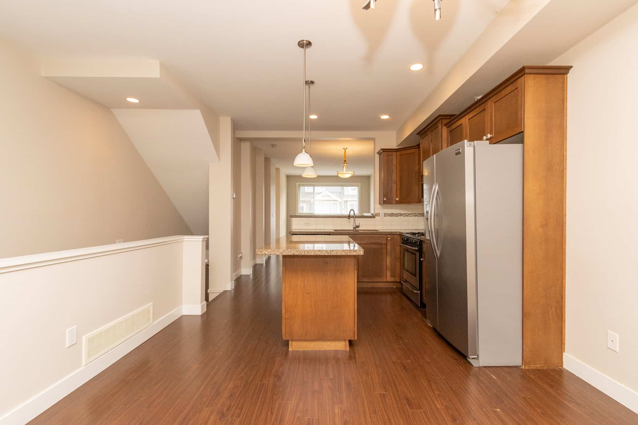 IMG_1795 Modern kitchen with stainless steel appliances, wooden cabinetry, granite countertops, and hardwood flooring, ideal for Vancouver homebuyers and real estate listings.