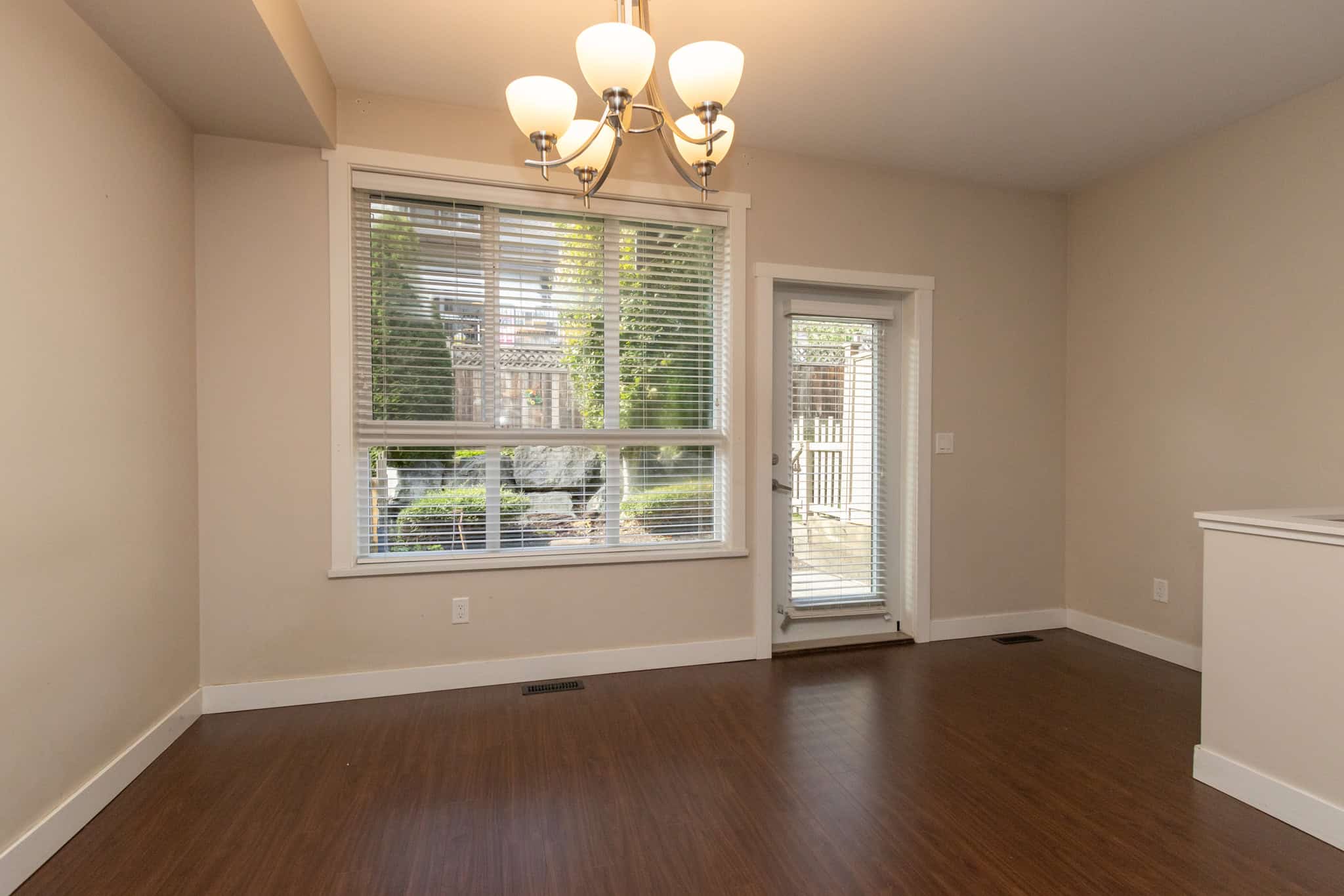 IMG_1801 Bright dining area with large window and door access to backyard, featuring hardwood flooring and modern lighting, ideal for Vancouver homebuyers seeking stylish and functional living spaces.