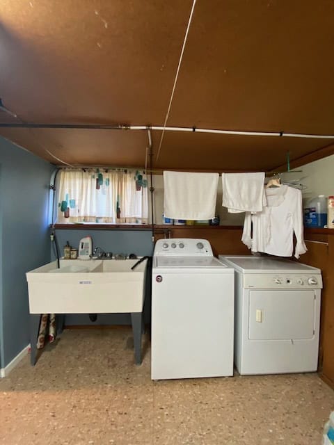 Clothes laundry area with washing machine, dryer, and utility sink in a cozy home laundry room.