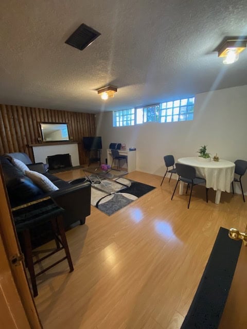 Bright living room with wood flooring, comfortable sofa, flat-screen TV, and cozy dining area featuring a round table and modern chairs, perfect for family gatherings or relaxing evenings.