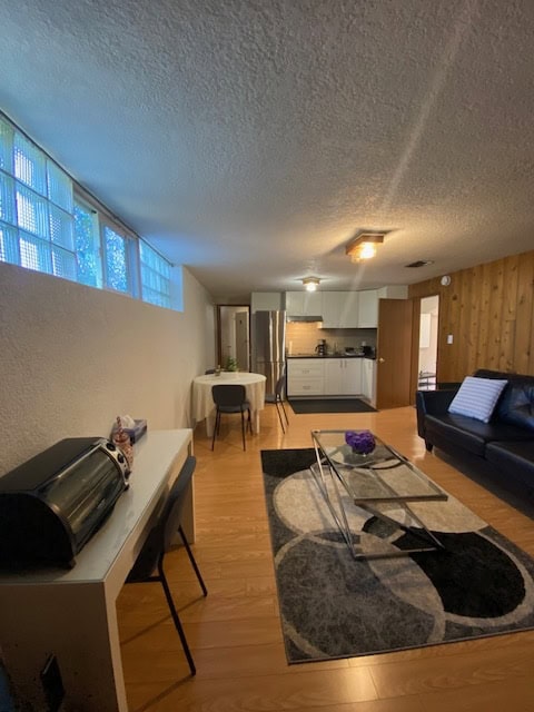 Modern living room with open kitchen in a Vancouver-area home, featuring stylish furniture, hardwood floors, and natural light, ideal for Vancouver real estate listings.