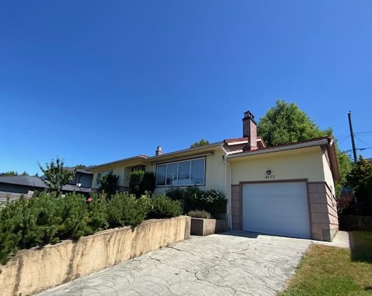 Spacious family home with a large driveway and garage, modern design, situated in a quiet neighbourhood with lush greenery and a well-maintained yard.