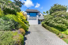 Modern residential property with landscaped gardens and a driveway leading to a contemporary house, showcasing luxury real estate in Vancouver.