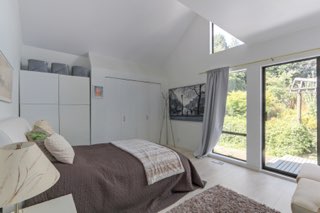 Orcaa realty inc modern bedroom with large windows and scenic greenery in Vancouver, BC.