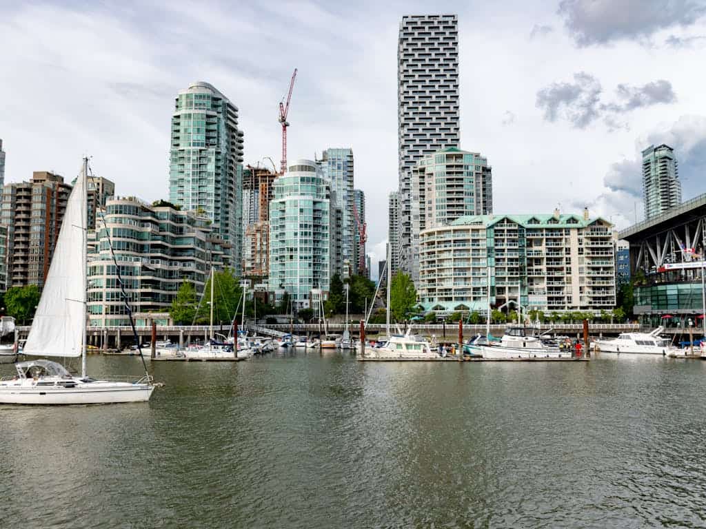 Modern Vancouver waterfront with luxury condos, marina, and high-rise buildings in the background, showcasing prime real estate and scenic views in the city.